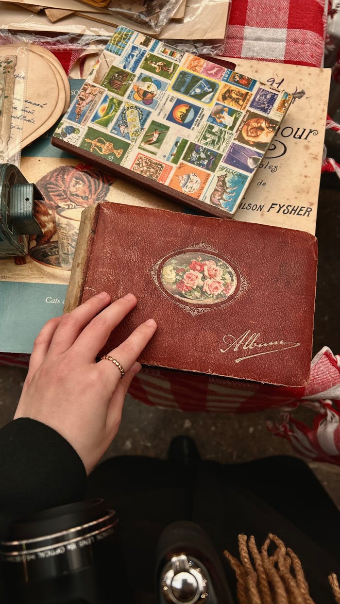 A vintage scrapbook with old postcards and books on a red checkered tablecloth.